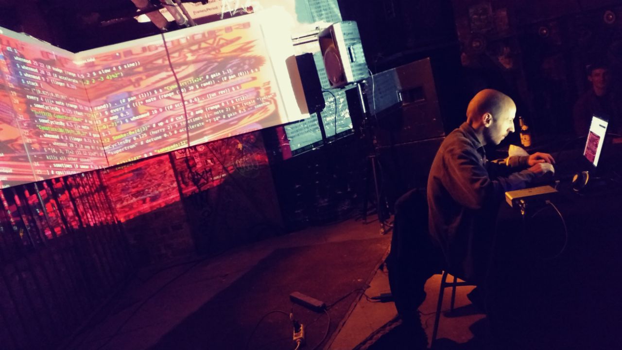 Staxl in front of his computer during livecoding performances with projections of his desktop on the wall